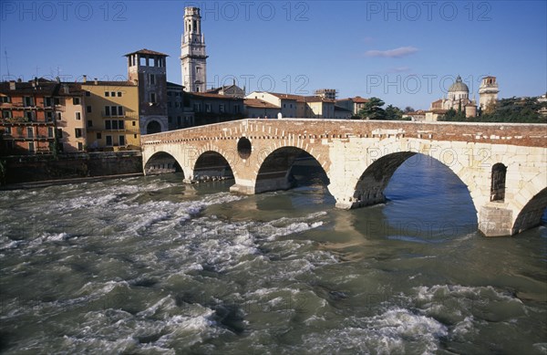 ITALY, Veneto, Verona, "Bridge across the River Adige with city buildings, tiled and domed rooftops beyond."
