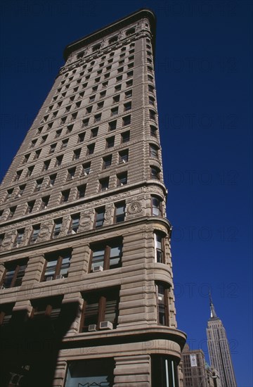 USA, New York, New York City, "Part view of the Flatiron Building from 23rd Street.  Steel framed, Beaux-Arts skyscraper designed by architect Daniel Burnham in 1902 to a triangular plan. "