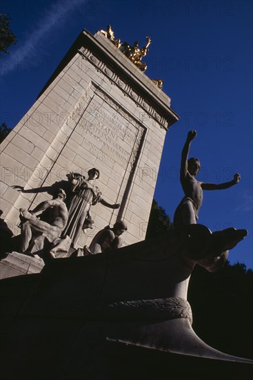 USA, New York, New York City, The Maine Monument  at the Merchants Gate entrance to Central Park.  Limestone pylon crowned with gilded bronze statue of Columbia triumphant.   Dedicated to the 260 seamen who died on the battleship Maine in 1898.  Beaux-arts sculpture by Attilio Piccirilli.