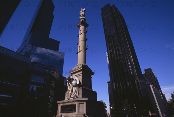 USA, New York, New York City, Columbus Circle.  Marble statue of Columbus on granite column decorated with bronze reliefs and angel holding globe at pedestal.  Times Warner building in background. Erected to commemorate the 400th anniversary of Columbus’ first voyage to the Americas.  Designed by sculptor Gaetano Russo.  Point at which distances to and from New York City are officially measured.