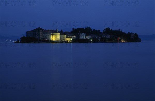 ITALY, Piedmont, Lake Maggiore, Borromeo Islands.  View across lake towards small rocky island of Isola Bella with Palazzo Borromeo illuminated at night.