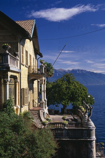 ITALY, Lake Maggiore, Part view of yellow painted exterior facade of villa with stone balustrade overlooking lake.