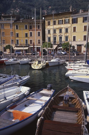 ITALY, Lombardy, Lake Garda, Gargnano.  Waterside buildings with boats moored in harbour in the foreground.