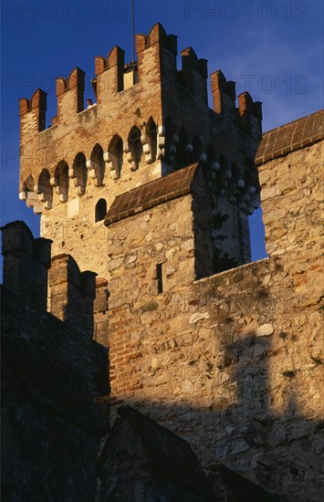 ITALY, Lombardy, Lake Garda , "Sirmione.  Rocca Scaligera medieval castle, detail of fortified tower and crenellated walls with visitor looking out from tower top."
