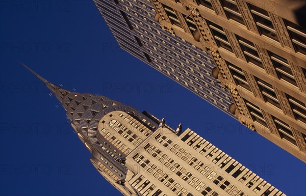 USA, New York, New York City, Angled view of the Chrysler Building from Lexington Avenue beside ornamented tower block exterior.  Steel framed Art Deco skyscraper built 1928-1930. Designed by architect William Van Alen.