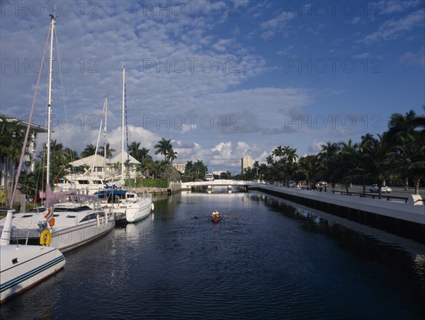 USA, Florida, Fort Lauderdale, Boats and waterside homes with a man traveling in a canoe on the water