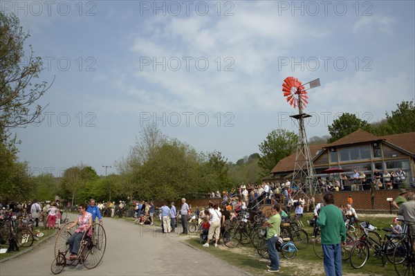 ENGLAND, West Sussex, Amberley, Amberley Working Museum. Veteran Cycle Day Grand Parade. Woman riding a bicycle with visitors watching.