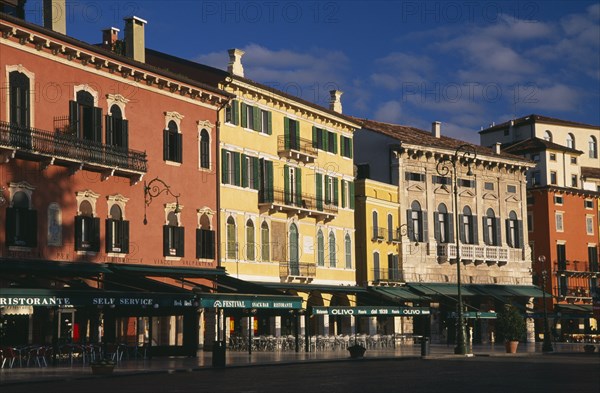 ITALY, Veneto, Verona, Piazza Bra.  Line of empty bars and cafes and painted facades of architecture overlooking square.