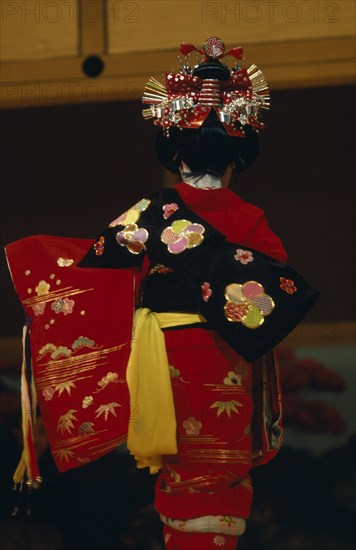 JAPAN, People, Children, "Young girl seen from behind, wearing traditional red embroidered kimono with black sash or obi and red and silver hair decoration during festival of the shrines and temples."