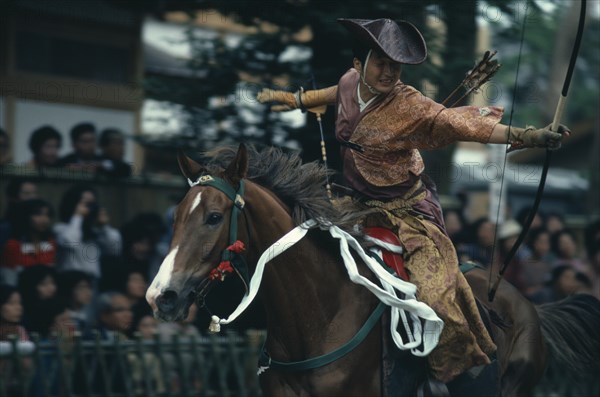 JAPAN, Honshu, Kamakura, Yabusame mounted archery at Hachimangu shrine festival.  Horseback archery has been a feature of the shrine’s festival since the early days of the Kamakura period (1192-1333) and this rider wears a samurai costume of the thirteenth century.  Yabusame is performed as an act of purity at Shinto shrines.