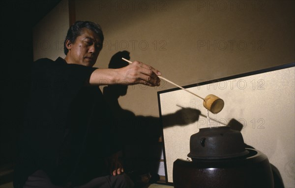 JAPAN, Honshu, Kyoto, "Grand Tea Master Sen Soshitsu pouring water from kettle or kama heated on charcoal burner or furo using long, stemmed bamboo ladle or hishaku."