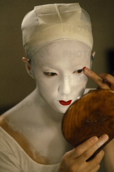 JAPAN, Arts, Performance, Kabuki actor Tamasaburo looking in hand mirror to apply make-up for role of Izayoi the courtesan turned crook in ‘The Village School’.  In kabuki all female roles are played by male actors or onnagata.