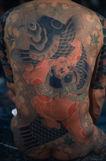 JAPAN, People, Yakuza, "Heavily tattooed back of gangster or Yakuza gang member in public bath house.  Design depicts a carp, a symbol of vigour and energy, ‘ikioi’, from its ability to swim against the current and leap waterfalls."