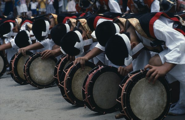 JAPAN, Kyushu, Kaseda Shrine, Line of bowed musicians at village festival.  In feudal times Kyushu was notable for the power of its great daimyo families and the festival celebrates the samurai with traditional dance and displays of martial arts.