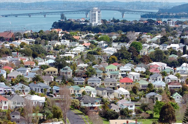NEW ZEALAND, NORTH ISLAND, AUCKLAND, GENERAL VIEW OF THE RESIDENTIAL DISTRICT OF DEVENPORT IN THE FOREGROUND AND ON TO STANLEY POINT AND AUCKLANDS HARBOUR BRIDGE CARRYING ROUTE 1 MOTORWAY CROSSING WAITEMATA HARBOUR IN THE DISTANCE.