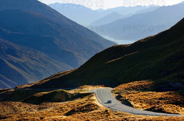 NEW ZEALAND, SOUTH ISLAND, OTAGO, "ARROWTOWN, THE CROWN RANGE ROAD FROM CARDRONA TO ARROWTOWN WITH THE MOUNTAIN RANGE KNOWN AS THE REMARKABLES AT QUEENSTOWN ON THE HORIZON."