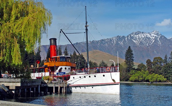 NEW ZEALAND, SOUTH ISLAND, OTAGO, "QUEENSTOWN, VINTAGE STEAMSHIP TSS EARNSALW DOCKED AT STEAMER WHARF QUEENSTOWN WHICH TAKES TOURISTS FOR CRUISES ON LAKE WAKATIPU WITH THE REMARKABLES MOUNTAINS BEHIND."