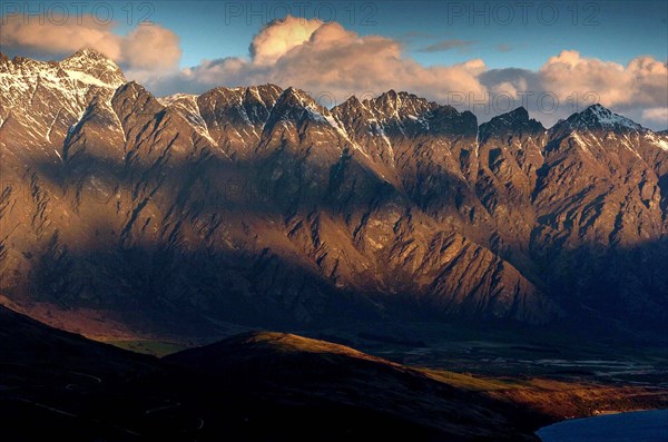 NEW ZEALAND, SOUTH ISLAND, OTAGO, "QUEENSTOWN, SHADOWS OF CLOUDS UPON THE REMARKABLES MOUNTAIN RANGE FROM THE SKYLINE RESTAURANT,CAFE AND GONDOLA COMPLEX ABOVE QUEENSTOWN AT SUNSET."