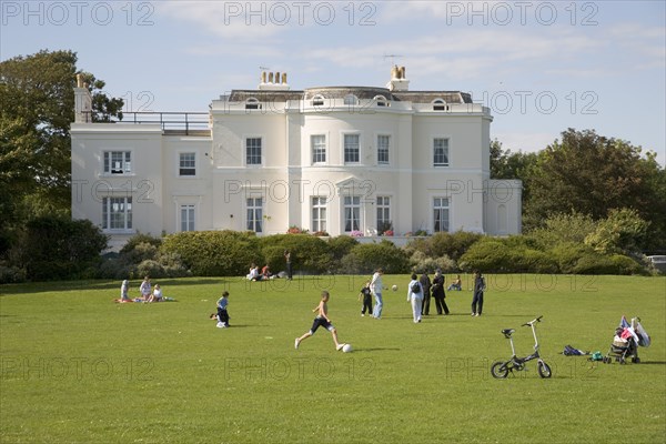 ENGLAND, West Sussex, Worthing, "View of the rear of Beach House, seen from the grounds with families and children playing football on the grass "
