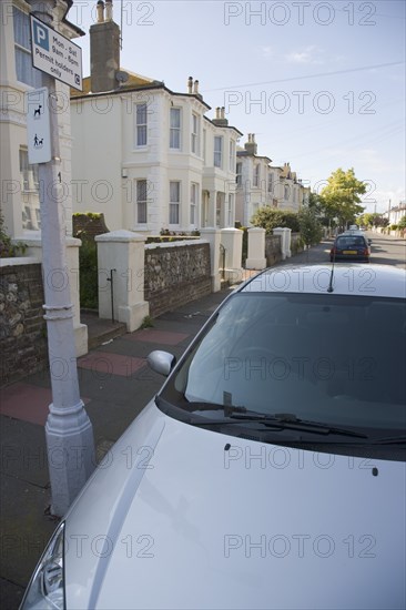 ENGLAND, West Sussex, Worthing, View over car bonnet parked next to lamp post with Permit holders only parking sign in residential street.