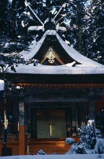 JAPAN, Honshu, Wakayama, "Mount Koyosan.  Shinto shrine in thick layer of snow over roof, ground and surrounding trees.  Shinto worship entails a belief in ancestor and nature spirits."