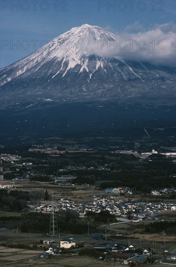 JAPAN, Honshu, Mount Fuji, Snow capped peak of Mount Fuji rising up behind houses and agricultural land.