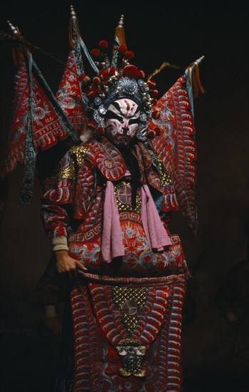 CHINA, Shanxi, Taiyuan, "Performer in traditional Chinese opera wearing elaborate red and blue costume with dramatic black, white and red face paint."