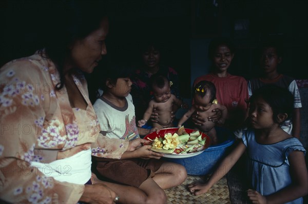 INDONESIA, Bali, Kuta, "Family group with twin babies.  In Bali, village people see the birth of girl and boy twins as an evil omen which requires exorcism rituals to make atonement for the ‘incestuous union’ of brother and sister in their mother’s womb.  The birth of same sex twins is seen as normal. "