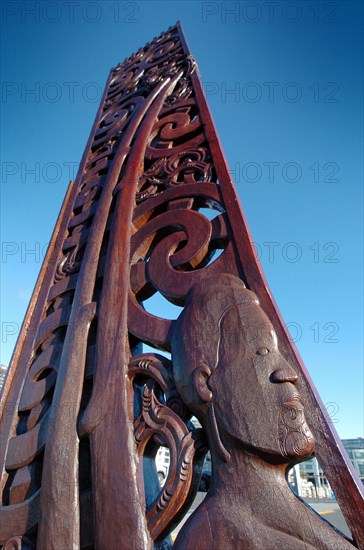 NEW ZEALAND, NORTH ISLAND, AUCKLAND, A MAORI CARVING FROM A FORMER LONG BOAT CEMENTED INTO AUCKLAND HARBOUR QUAYSIDE