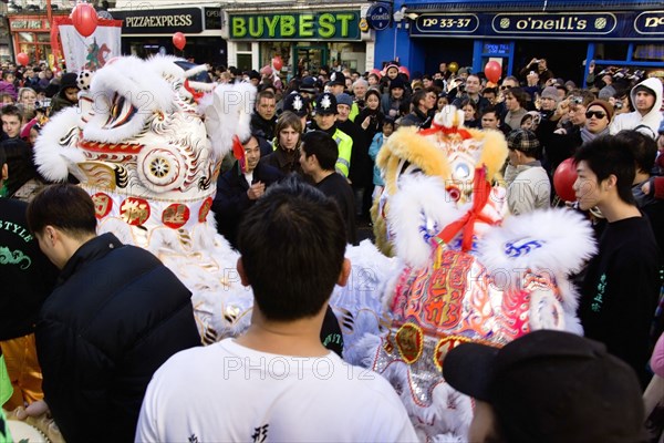 ENGLAND, London, Chinatown, Crowds passing under paper lanterns hung around one of the oriental ornamental gates or paifang in Gerrard Street during Chinese New Year celebrations in 2006 for the coming Year of The Dog