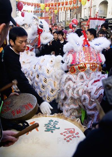 ENGLAND, London, Chinatown, Lion Dance troupe performing in Wardour Street amongst the crowd outside a restaurant during Chinese New Year celebrations in 2006 for the coming Year of The Dog