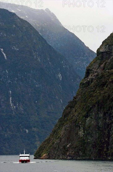 NEW ZEALAND, SOUTH ISLAND, "MILFORD SOUND,", "SOUTHLAND, A CRUISE BOAT TRAVELS ALONG MILFORD SOUND IN NEW ZEALANDS FJORDLAND AREA."