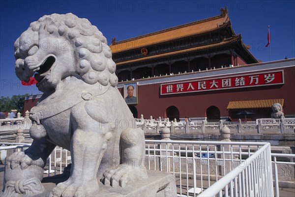 CHINA, Beijing, Entrance gateway to the Forbidden City from Tiananmen Square with portrait of Mao on exterior wall and stone statue of lion in foreground.