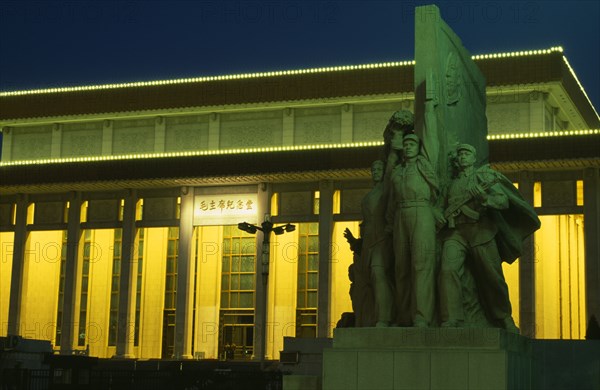 CHINA, Beijing, Tiananmen Square.  Mausoleum of Mao Zedong illuminated at night with statue in foreground.
