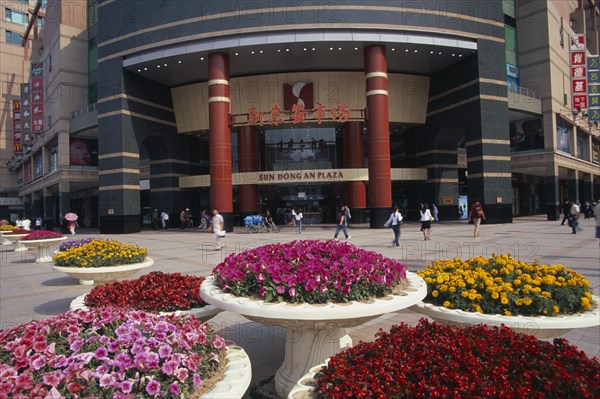 CHINA, Beijing, Raised circular flower beds outside Sun Dong an Plaza shopping mall entrance on Wangfujing street.