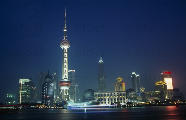 CHINA, Shanghai, Pudong at night with illuminated skyscrapers and buildings including the Oriental Pearl Tower and Jin Mao Building.