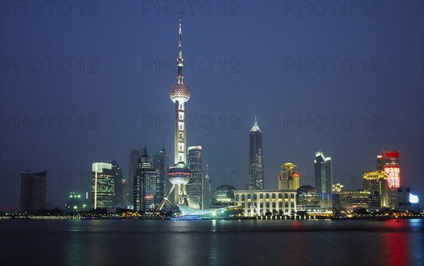 CHINA, Shanghai, Pudong at night with illuminated skyscrapers and buildings including the Oriental Pearl Tower and Jin Mao Building.