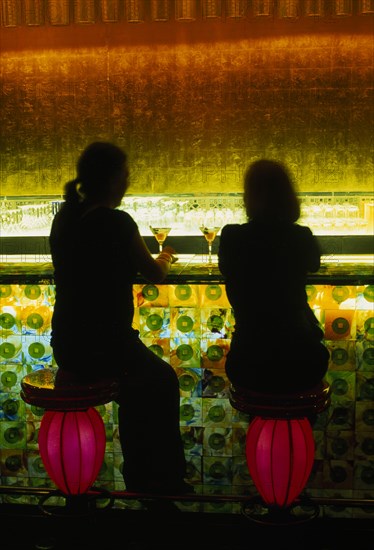 CHINA, Shanghai, Xintiandi District.  Tou Ming Si Kao ( TMSK ) bar interior with two figures having cocktails seated at illuminated glass bar on stools resembling Chinese lanterns.