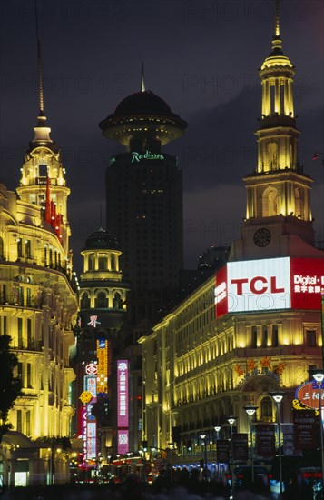 CHINA, Shanghai, "Nanjing Lu.  Looking towards Renmin Square or the People’s Square at night with illuminated buildings and neon signs.  Crowds in foreground, radio tower behind. "