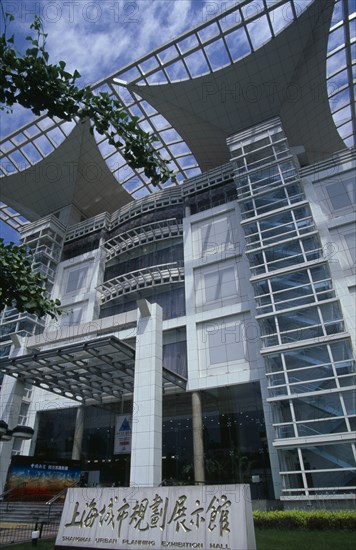 CHINA, Shanghai, "Shanghai Urban Planning Exhibition Hall, Renmin Square.  Modern, predominantly glass fronted exterior with branches of Ginko tree in foreground."