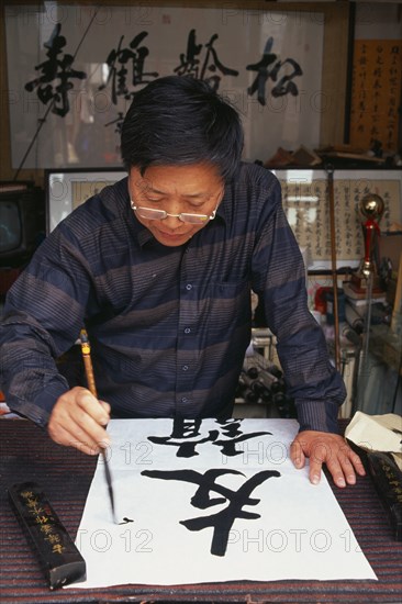 CHINA, Beijing, Caligrapher at work in Hutong workshop.
