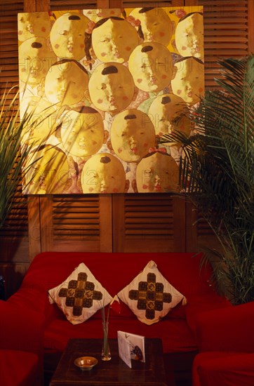 CHINA, Shanghai, "French Concession area.  Seating area in the Face Bar at the Ruijin Guest House.  Red sofa and chairs, potted plants, low wooden table and artwork on wall behind."