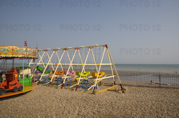 ENGLAND, West Sussex, Bognor Regis, Colourful children’s amusement rides on shingle beach