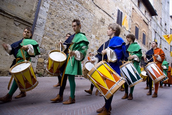 ITALY, Tuscany, San Gimignano, Boys and young men in Medieval costume beating drums in a parade through the streets during a pageant in the town
