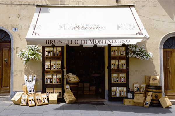 ITALY, Tuscany, Montalcino, Wine shop in the medieval hilltown with a display of wines on the pavement beside the doorway under a canopy