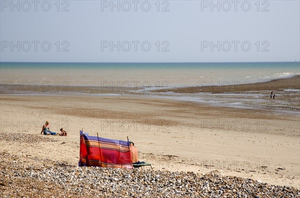 ENGLAND, West Sussex, Littlehampton, View towards the sea from beach with sunbathers behind colourful wind break on sand