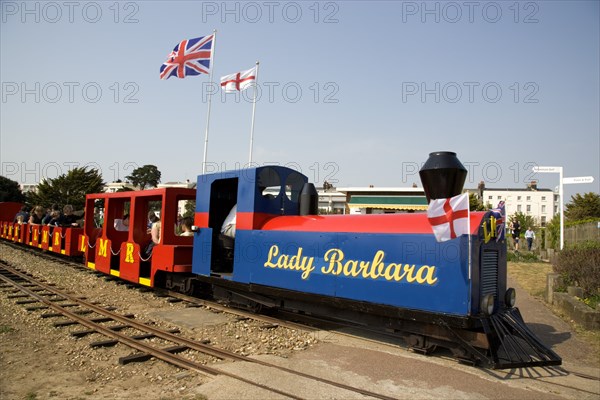 ENGLAND, West Sussex, Littlehampton, Families enjoying a miniature railway ride in Norfolk Gardens with Union Jack Flag flying behind.