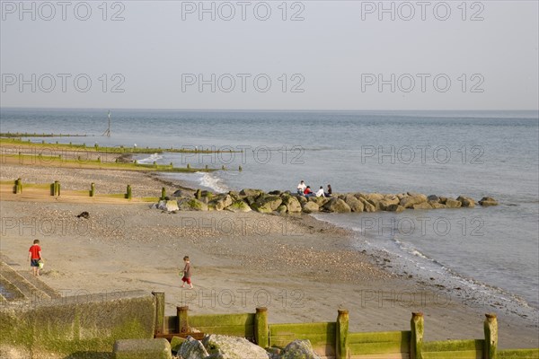ENGLAND, West Sussex, Selsey, Children playing with bucket and spade on sandy beach next to sea