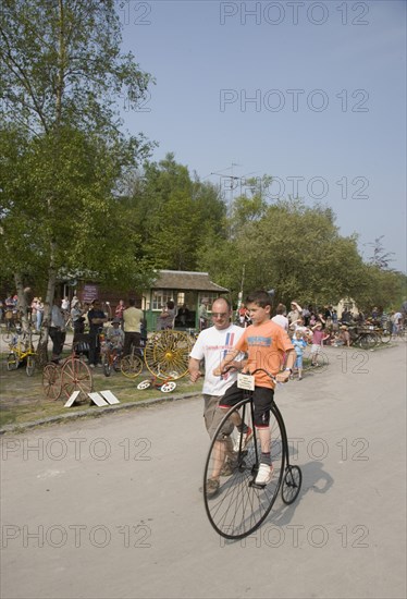 ENGLAND, West Sussex, Amberley, Amberley Working Museum. Veteran Cycle Day Grand Parade. Young Boy riding a small version Penny Farthing bicycle with visitors watching.