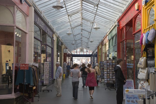 ENGLAND, West Sussex, Bognor Regis, Interior of The Bognor Arcade with people walking through in-between colourful shop fronts